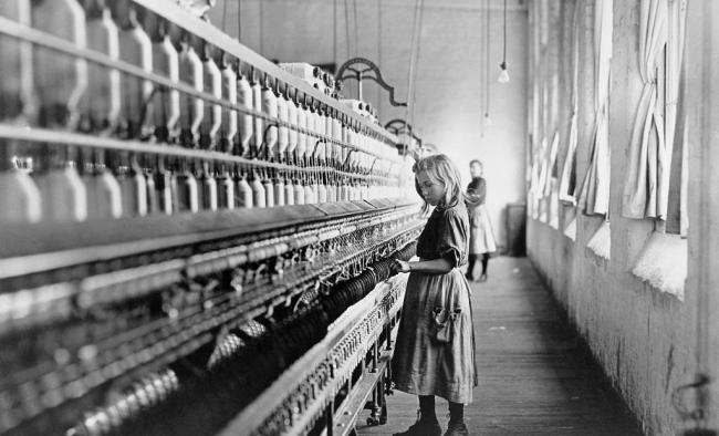 A young girl tends the spinning machine at a cotton mill in North Carolina. Children worked adult hours for pennies in mills and factories all over the United States until reforms came with the Fair Labor Standards Act of 1938