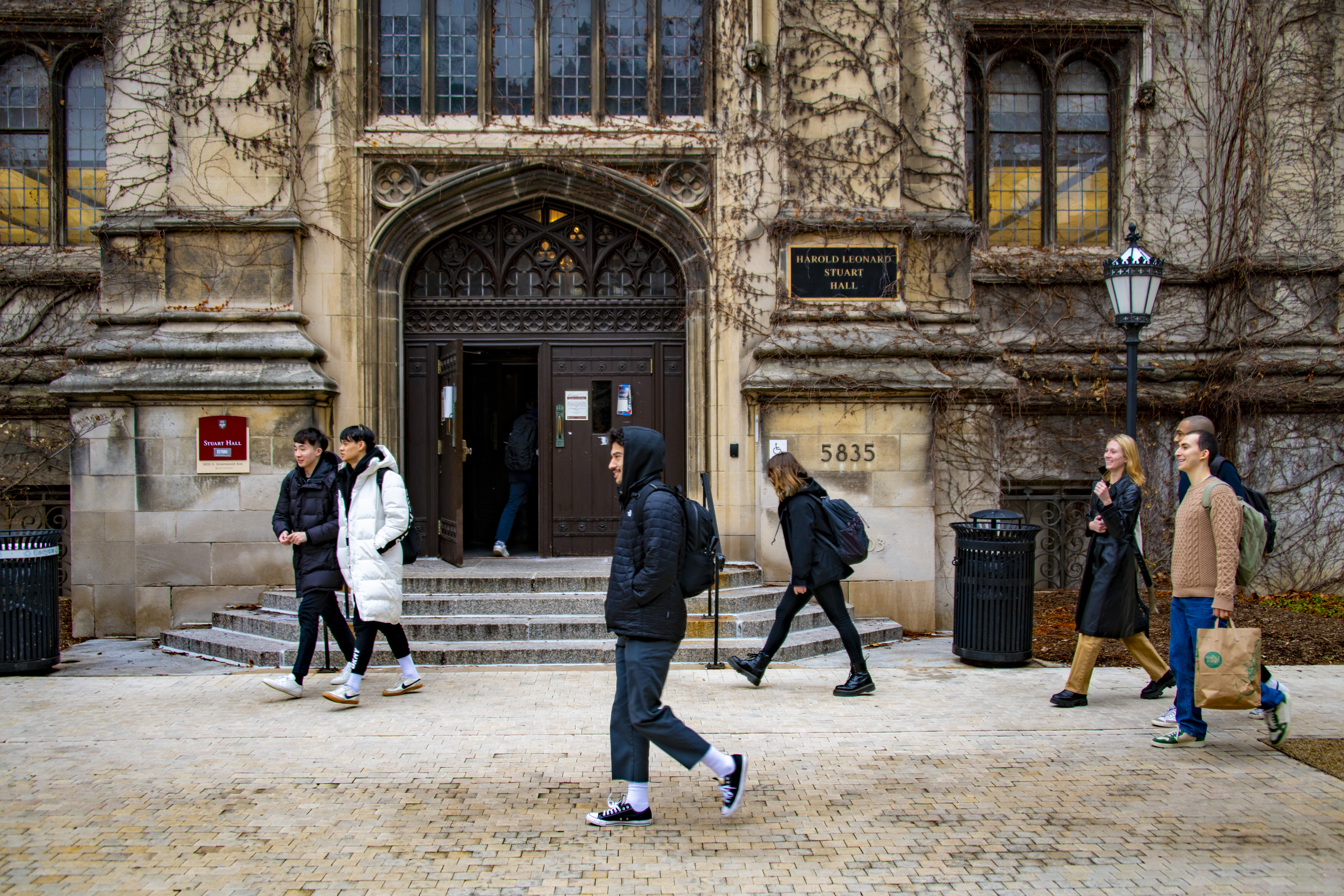 students walking in front of a stone building