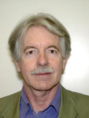 headshot of man with a green jacket and blue shirt