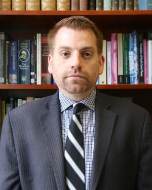 Man in suit and tie in front of a bookshelf