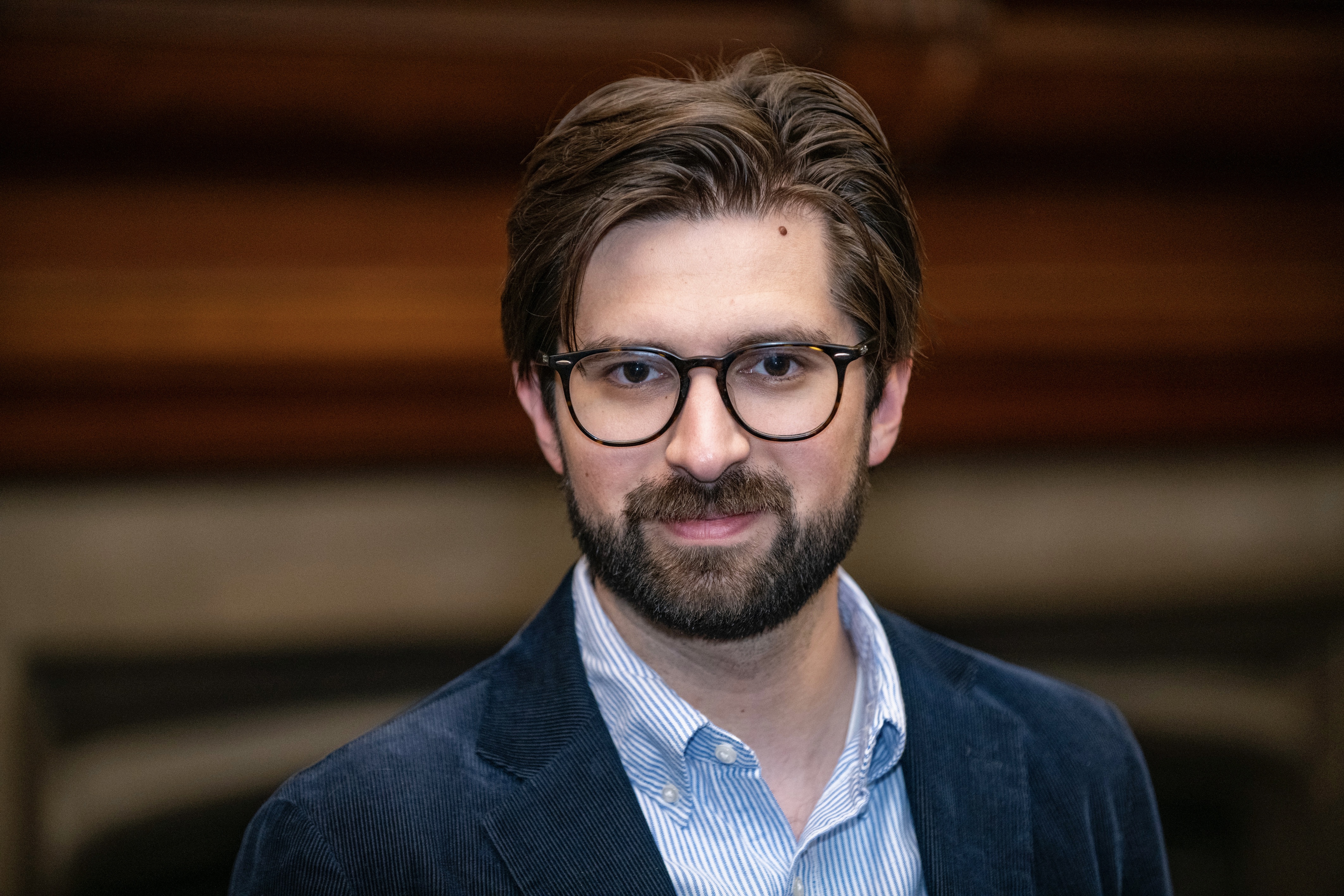 Headshot of a man in a suit jacket wearing glasses