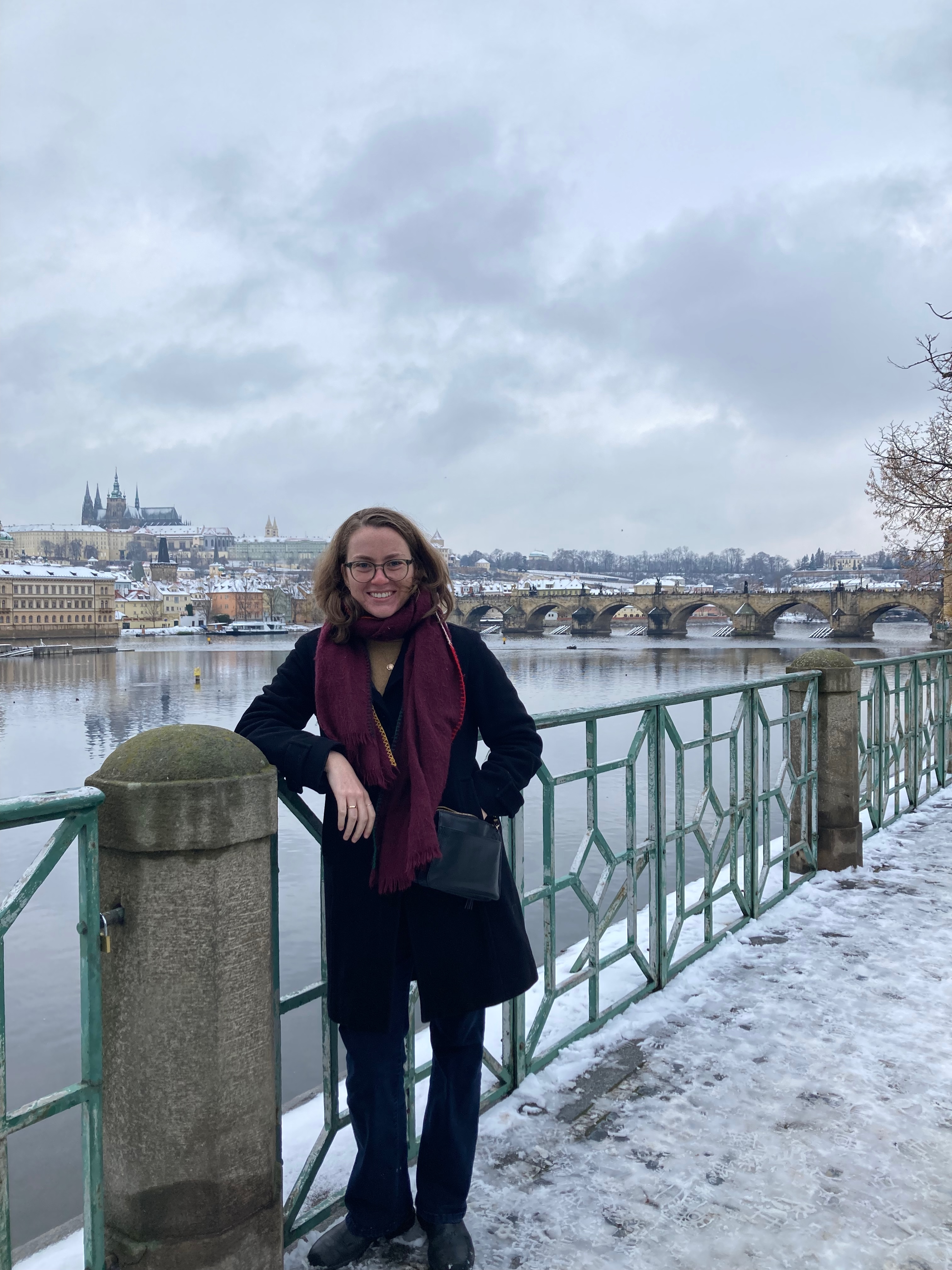 Julia Mead leaning against a rail on a riverwalk in Prague