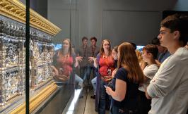 students looking at a Renaissance-era artifact with an instructor lecturing