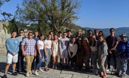 a group of people standing in front of a tree and mountains