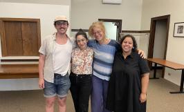 four people standing closely together in an open room