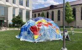 A dome with a colorful canvas covering in a grassy area