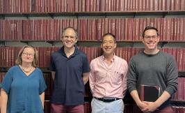 four people standing in front of wall of books