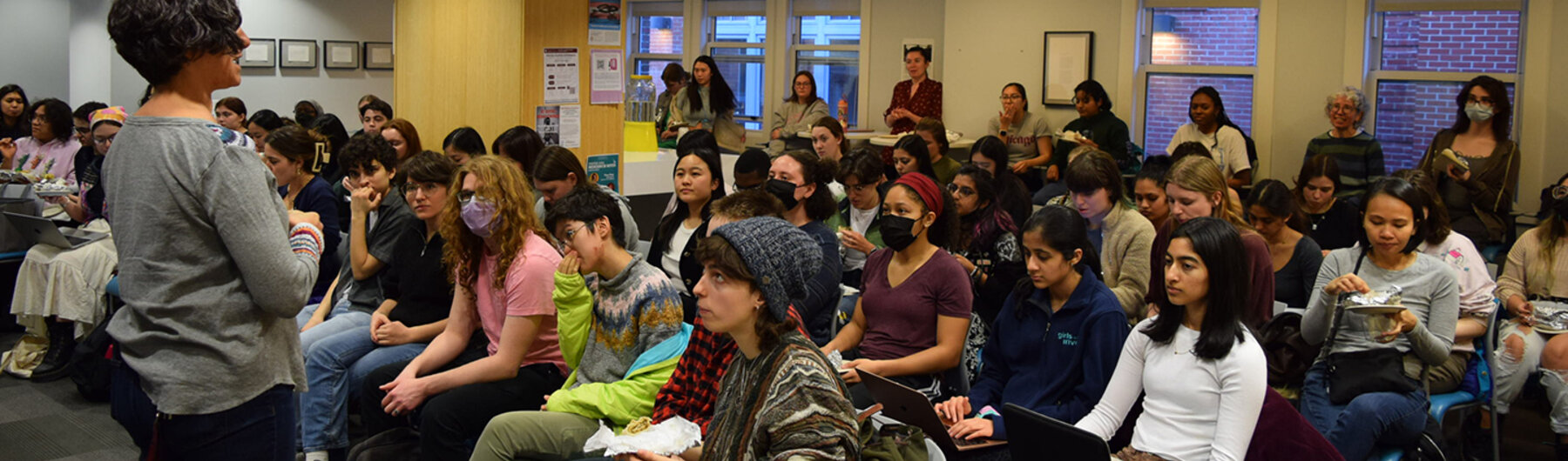 People seated and standing listening to a speaker.