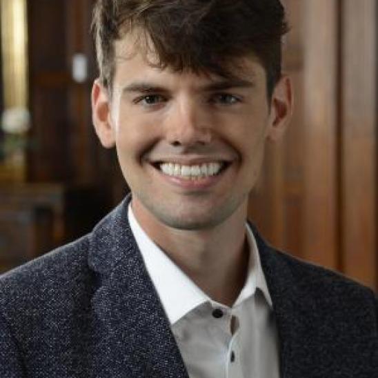 man in suit jacket in front of a wood wall