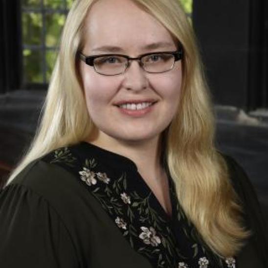 woman with long hair in a black shirt in front of a window